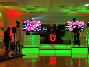 Custom LED neon sign displayed on a DJ booth during a fundraising gala event with branded lighting and entertainment staging.