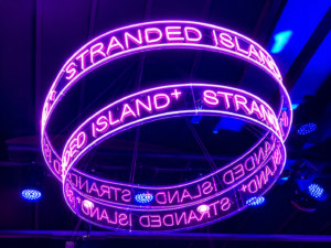 Custom tiered LED neon chandelier featuring illuminated acrylic rings suspended from the ceiling for experiential venue branding.