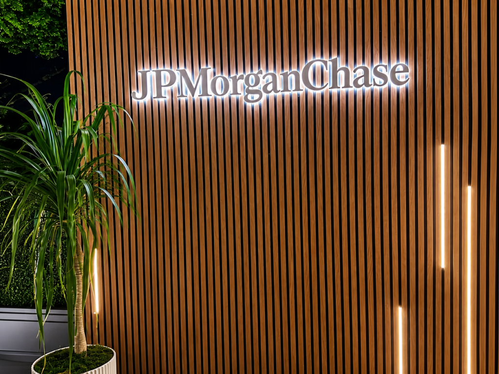 Custom white face reverse lit halo letters mounted on a wood slat wall for outdoor corporate event branding and hospitality environments.