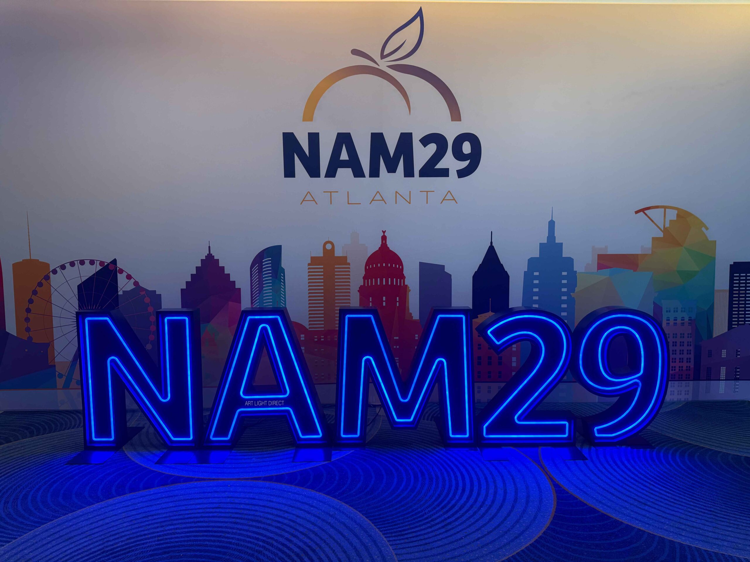Custom illuminated event letters for NAM29 with blue LED outlines displayed in front of an Atlanta skyline backdrop.