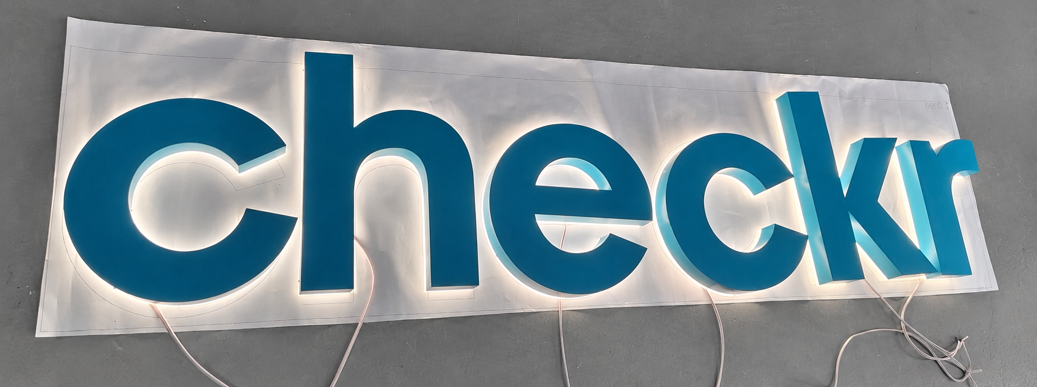 Illuminated teal Checkr halo-lit logo letters during production testing