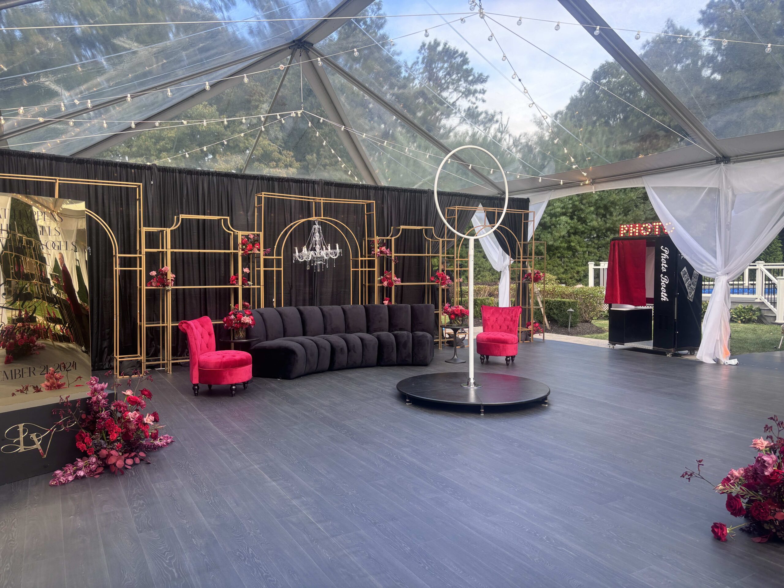 Custom marquee photo booth sign with illuminated red PHOTO letters installed above a black and red event booth inside a clear tent.
