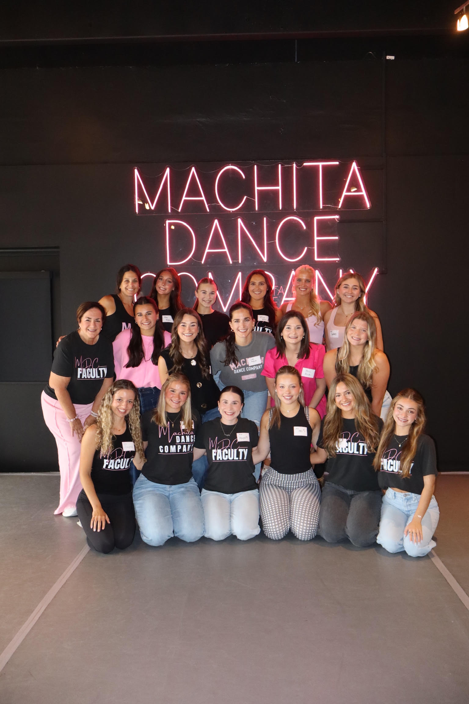 Machita Dance Company team in front of custom pink LED neon sign