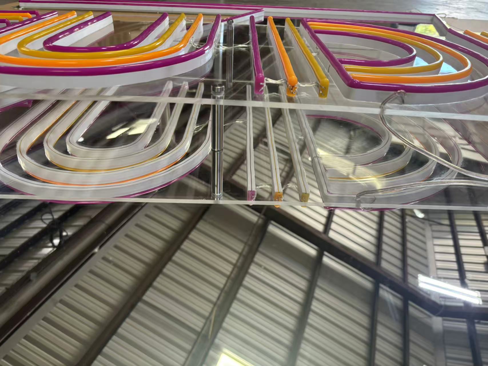 Studio 7 multicolor LED neon logo sign during production on a mirrored acrylic backer