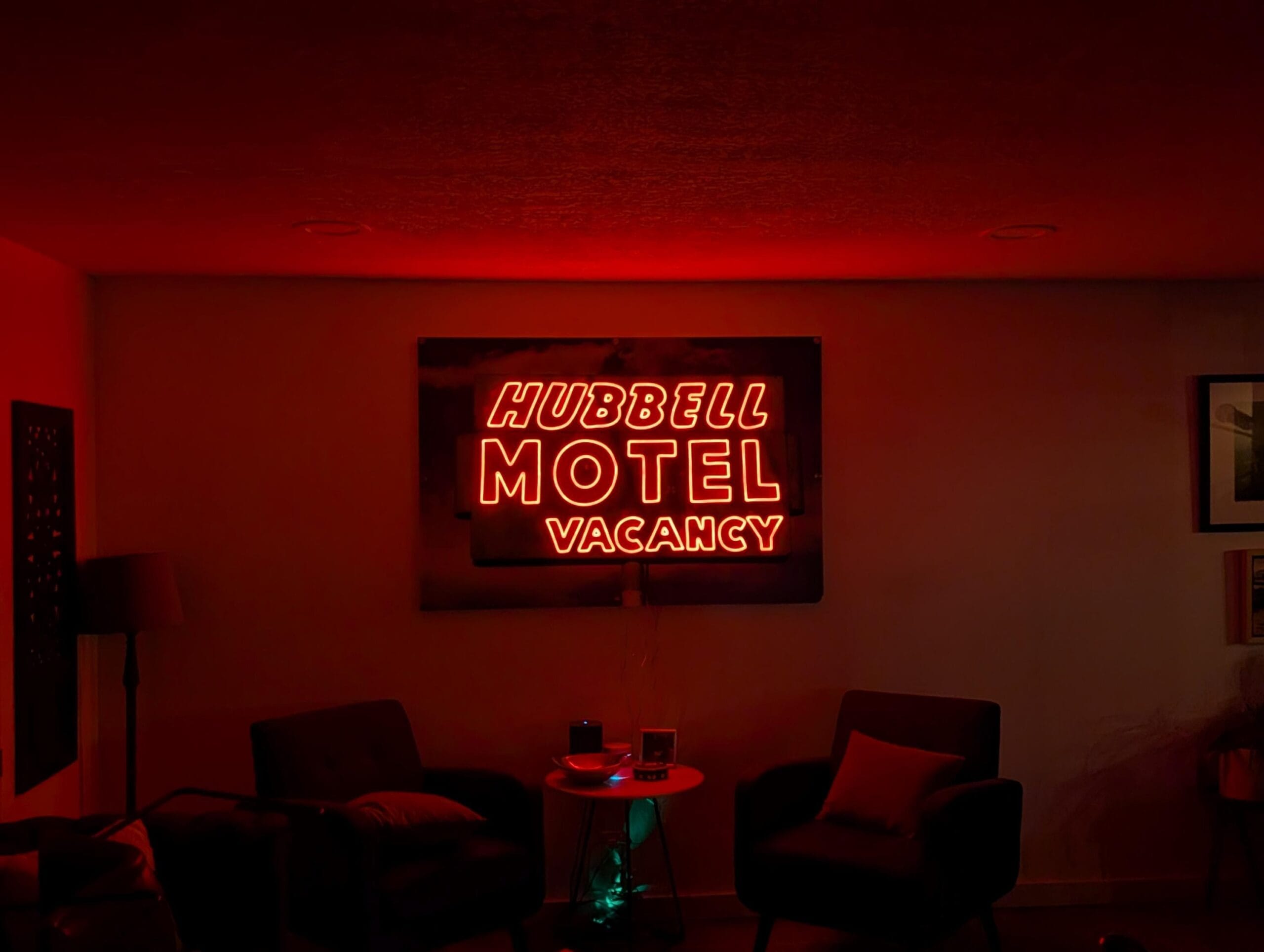 Hubbell Motel red LED neon glowing above a seating area in a darkened room