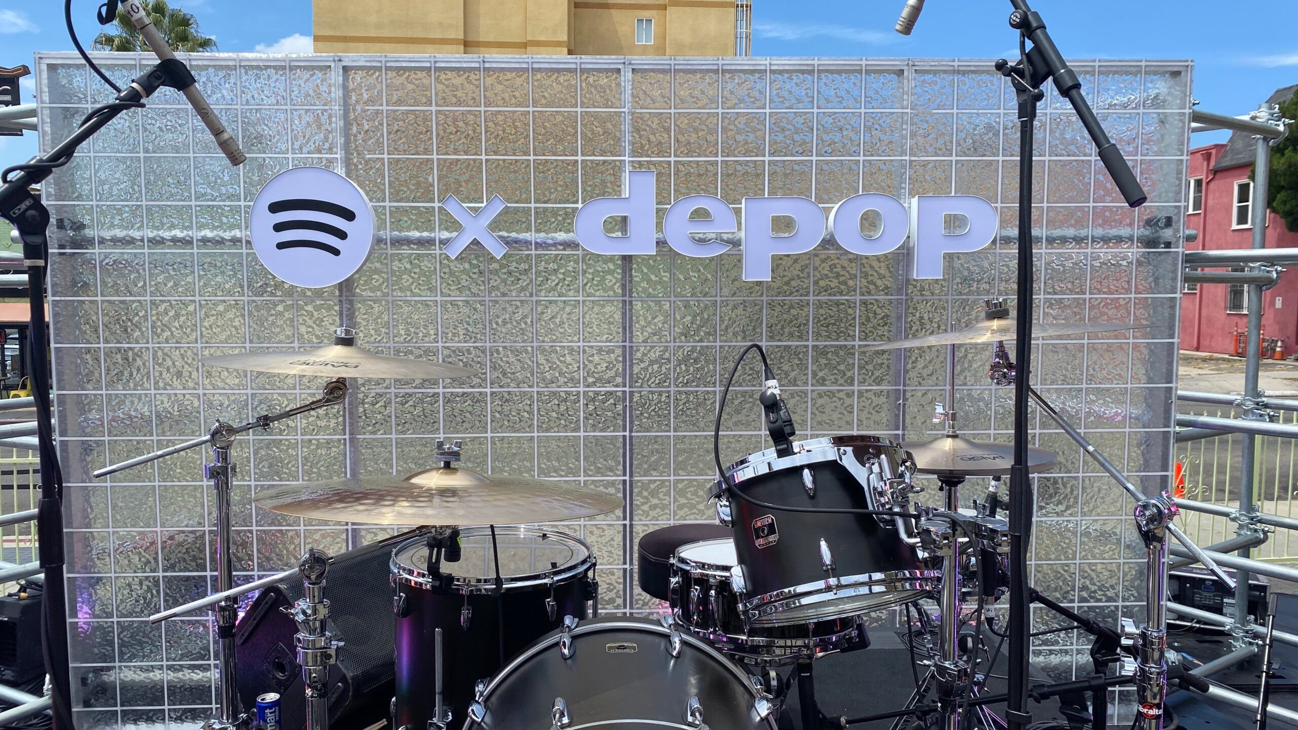 Spotify x Depop logo signage installed behind a drum kit on an outdoor stage